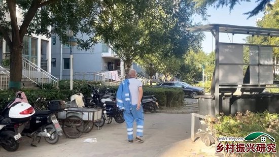 9月20日下午，北京某小区内，六十多岁的河南环卫工结束一天的工作，往住处走去。他住在单位提供的铁皮房里，三四人同住一间。摄影/郑可书